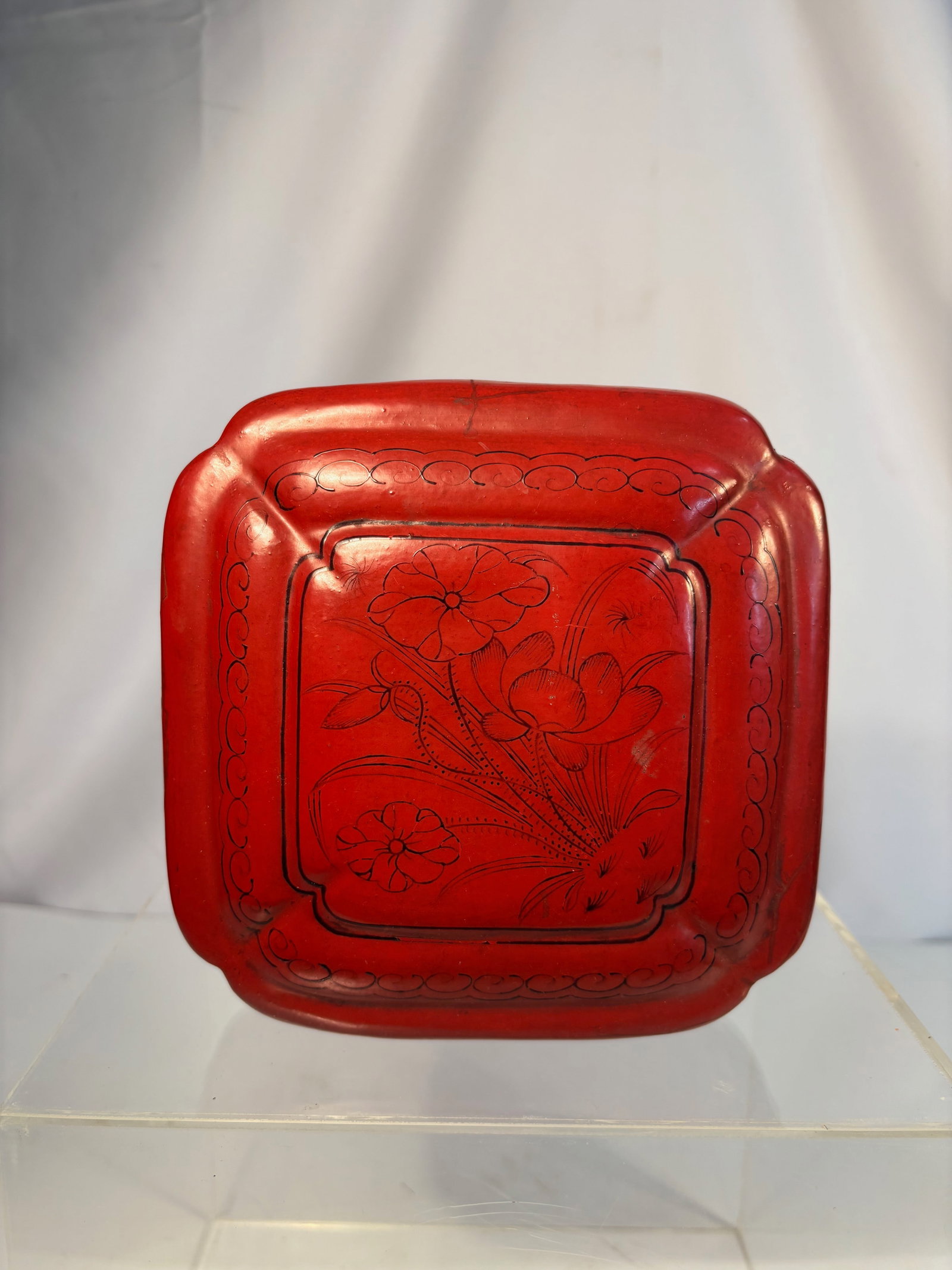 A Chinese Carved Cinnabar Lacquer Box with Floral Design, Ming to Early Qing dynasty (16th–18th: An elegant Chinese carved cinnabar lacquer box of quatrefoil-cushion form, the cover finely carved in relief with a central floral spray of peonies and scrolling foliage, framed by a band of ruyi-head