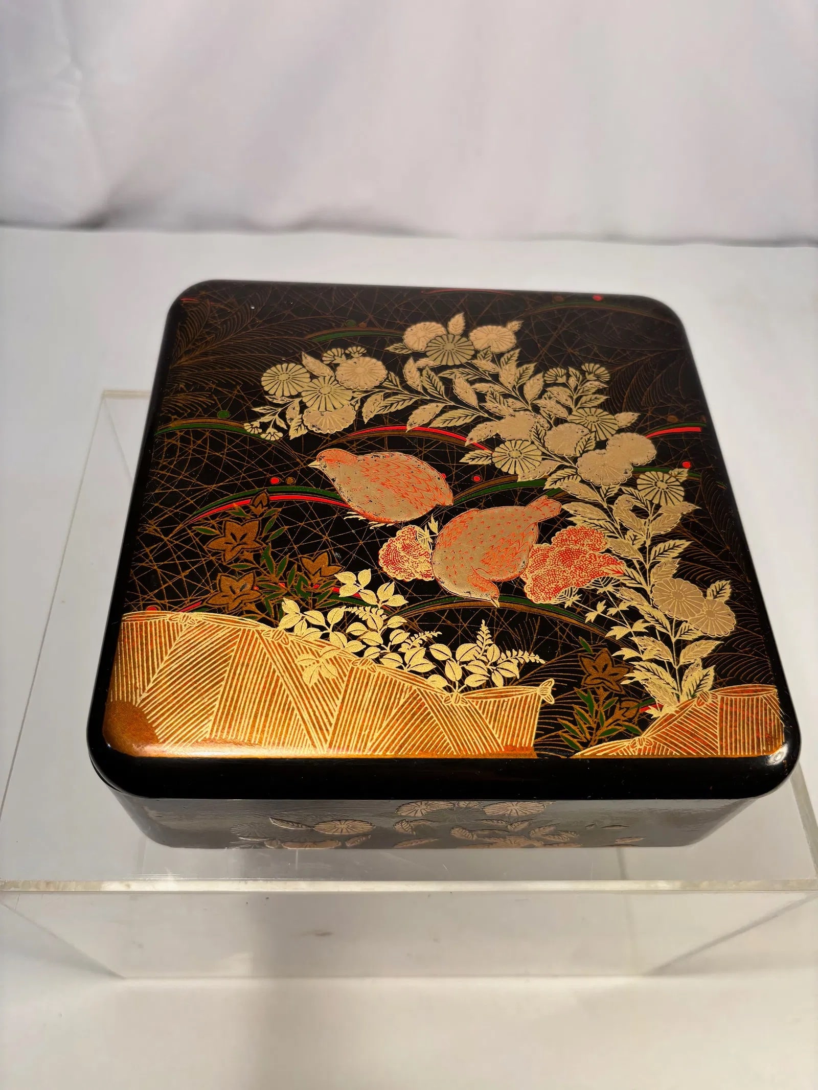 A Japanese Lacquer Box with Gilt Floral Decoration, Meiji Period (Late 19th Century): Japanese rectangular lacquer box, Meiji period (late 19th century), decorated in gilt and colored lacquer on a black ground. The lid features a dense floral composition with chrysanthemums and foliage