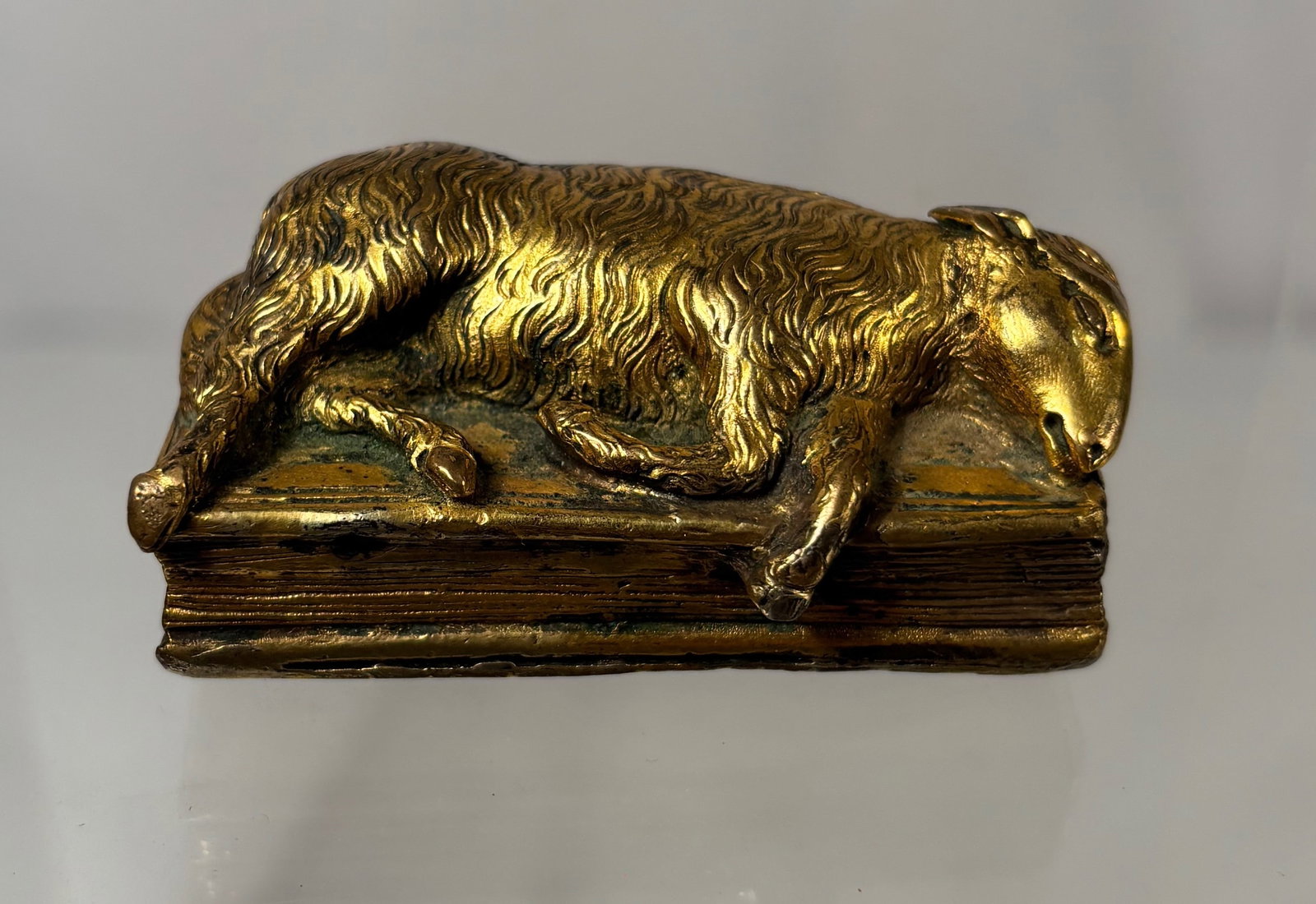 An European Gilt Bronze “Agnus Dei on the Holy Bible?? Box Lid, 19th Century: Featuring the symbolic Lamb of God (Agnus Dei) reclining atop a book representing the Holy Bible, a traditional Christian motif symbolizing sacrifice, purity, and divine authority. Likely from a 19th-