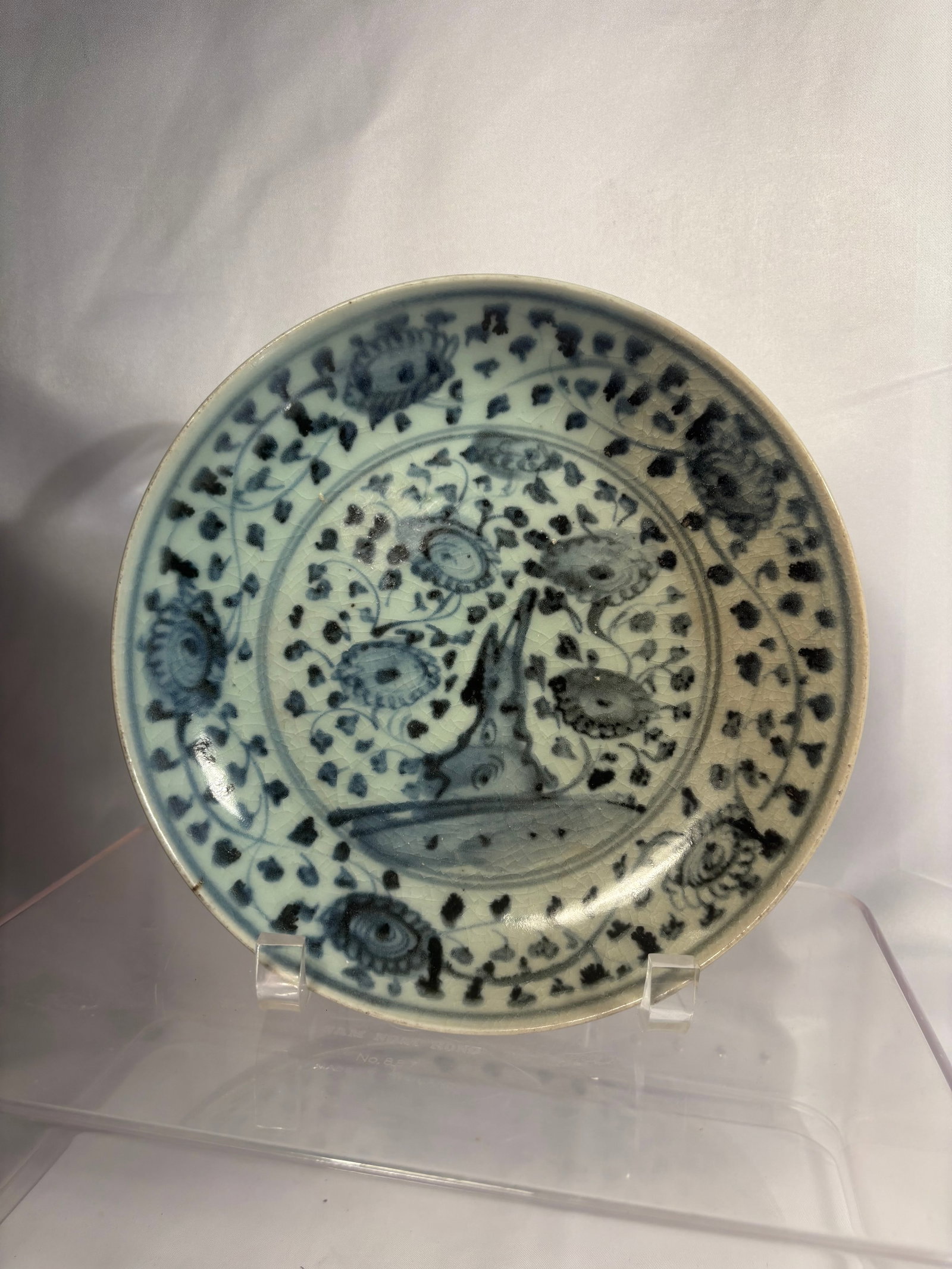 A Chinese Blue and White Phoenix and Floral Dish, Ming dynsaty(1368-1644): A Chinese blue and white porcelain dish dating to the Ming dynasty, freely painted with a stylized long-tailed phoenix amid dense flowering vines. The cavetto and broad rim are decorated with scrollin