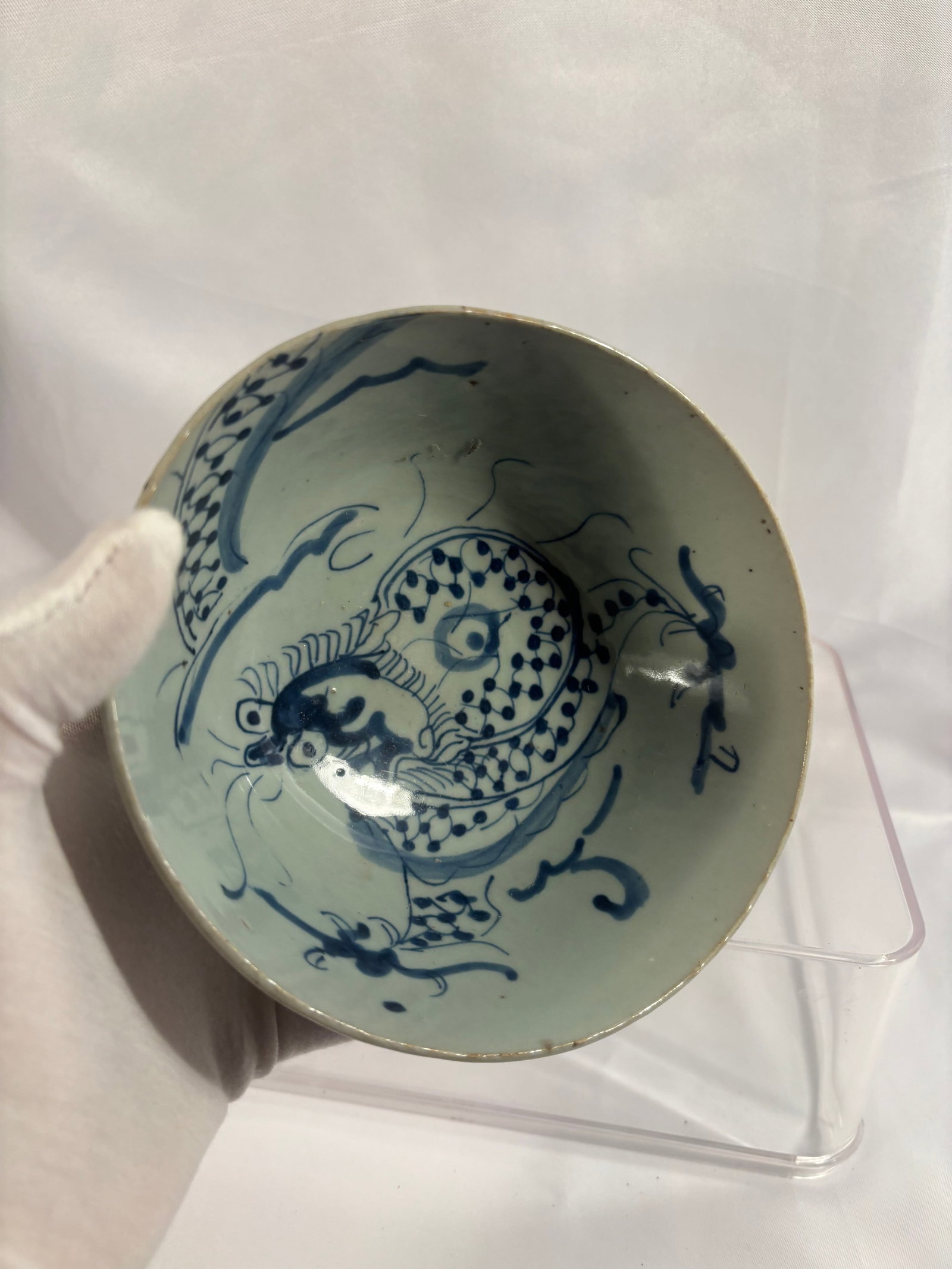 A Chinese Blue and White Dragon Bowl, Ming Dynasty (1368-1644): A Chinese blue and white porcelain bowl dating to the Ming dynasty, of deep rounded form supported on a short circular foot. The interior is boldly painted in underglaze blue with a coiled dragon purs