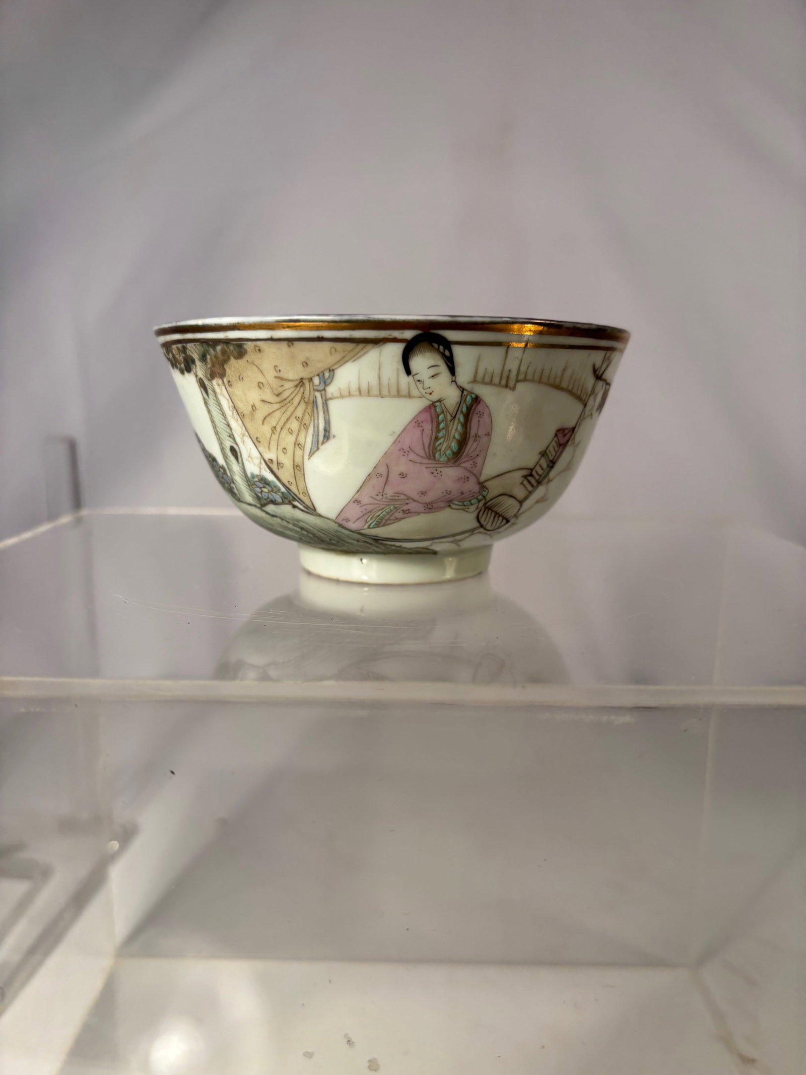A Chinese Famille Rose Figural Bowl, Marked: Early 20th century; A finely hand-painted famille rose porcelain bowl depicting an elegant lady seated in a pavilion interior, surrounded by curtains, scholarly objects, and garden elements. The scene