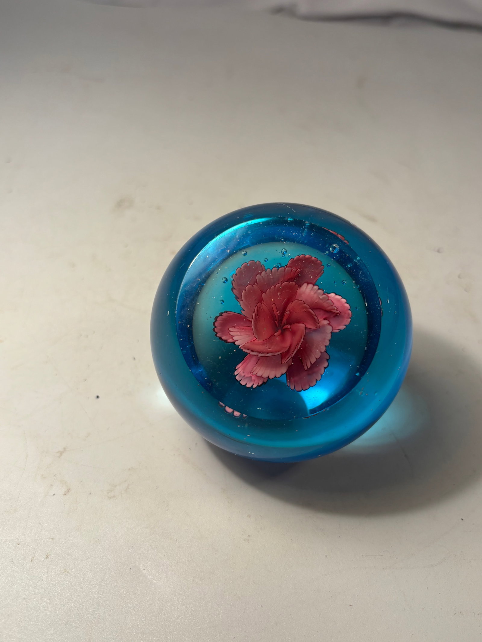 Vintage Blue Art Glass Floral Paperweight: A vintage spherical art-glass paperweight in vivid blue, enclosing a dimensional pink and red multi-petal flower with scattered controlled air bubbles. Finished with a polished circular pontil on the 
