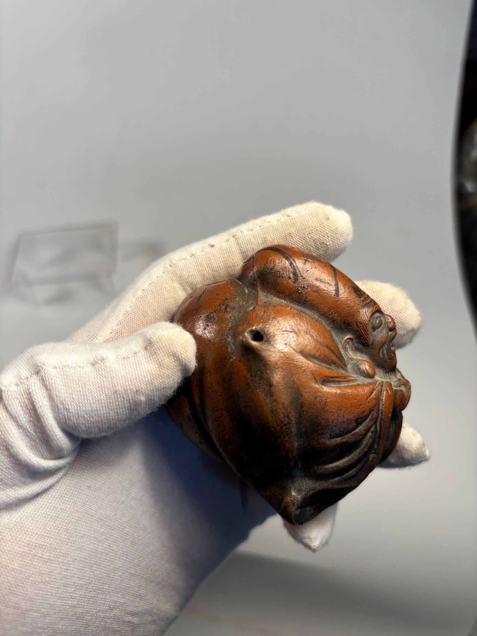A Japanese Ceramic Netsuke of Hotei: 19th century ,one finely molded ceramic netsuke depicting Hotei (the Laughing Buddha) with expressive features and robe detail, pierced for suspension; Dimensions? The Netsuke height: 2.25 inches,