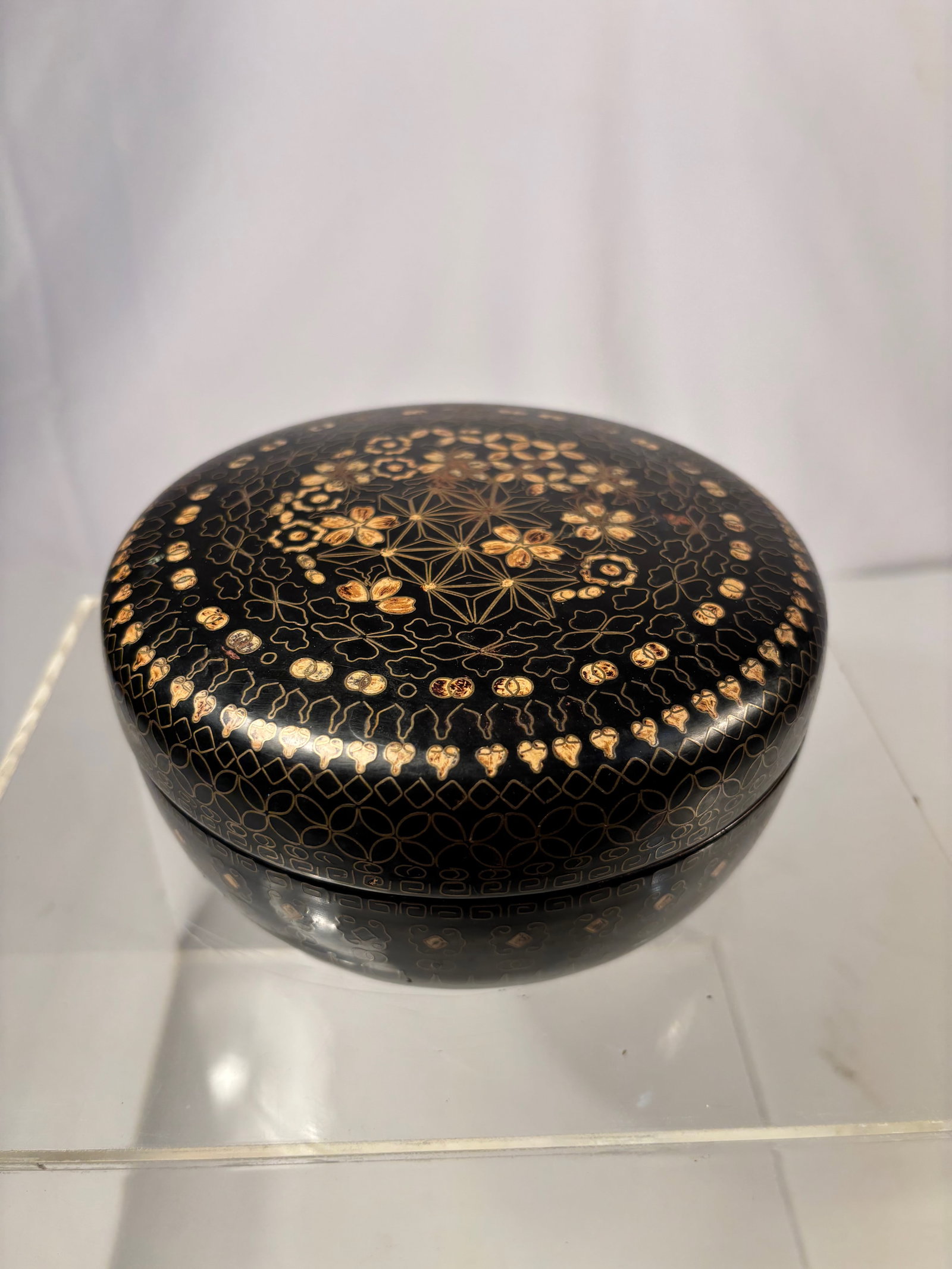 A Japanese Lacquered Wood Bowl with Copper Wire Inlay and Gilt Engraved Decoration, Early Meiji: A finely crafted Japanese black lacquered wood bowl inlaid with delicate copper wire forming interlocking geometric and floral patterns, enhanced with gilt engraving. The refined decoration exemplifie