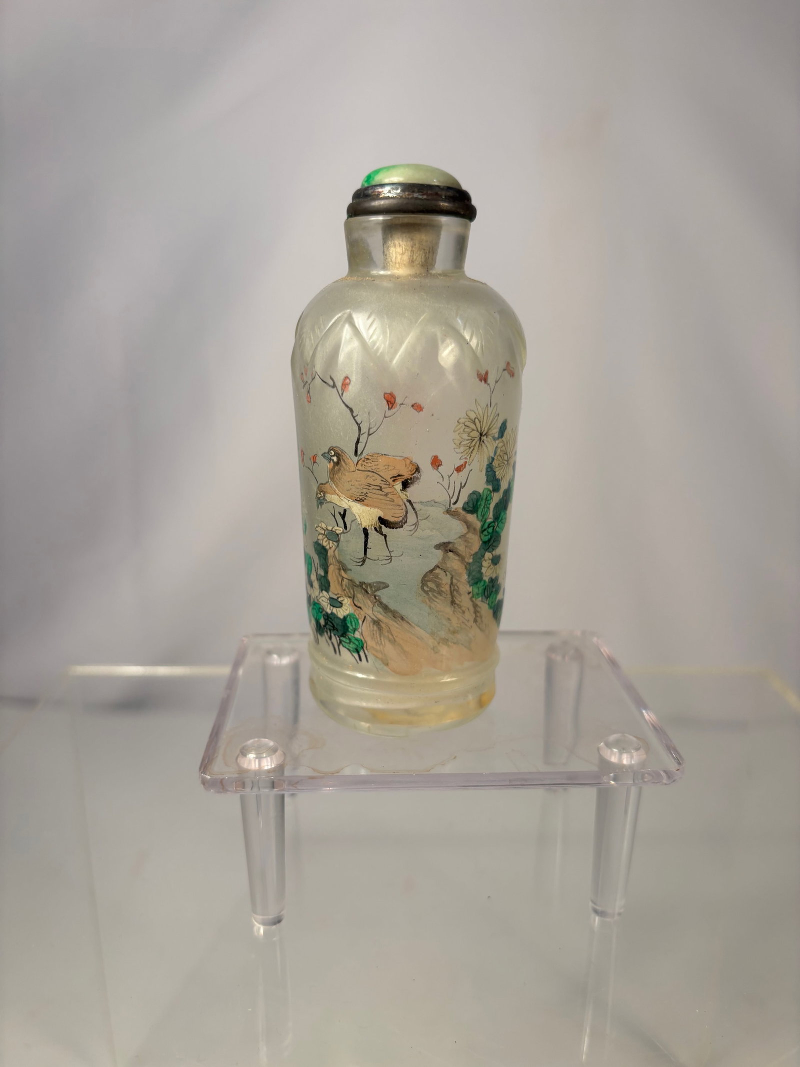A Chinese Inside-Painted Glass Snuff Bottle with Jadeite Stopper: Qing dynasty(1644-1912); Chinese inside-painted glass snuff bottle, decorated with a bird perched among flowering branches on one side and floral motifs on the reverse. The bottle is of flattened balu