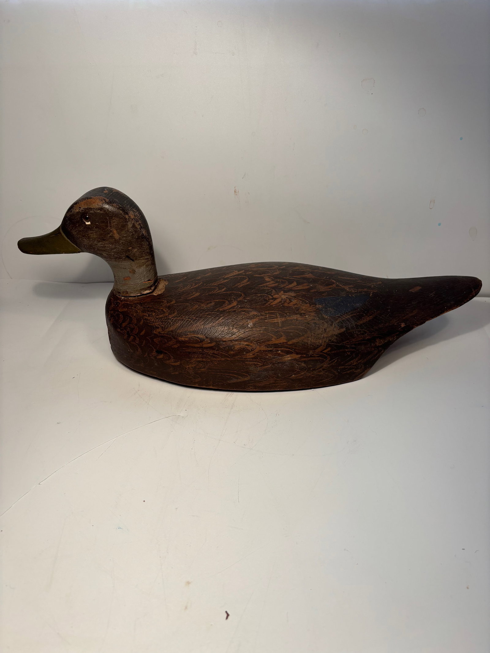 American Hand-Carved Wooden Duck Decoy with Carved Feather Detail: Early 20th century, A finely hand-carved wooden duck decoy, American, early 20th century. The body features deeply incised feather detailing and a separately attached head with traces of original pain