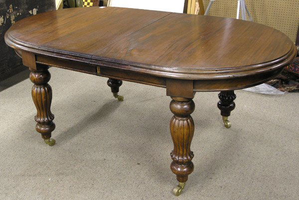 Continental Mahogany Dining Table: Carved continental mahogany dining table, the oval form having a double molded edge over a panaled frieize on four carved fluted vase and ball turned legs with two leaves, 73''l x 44''d x 32''h plus t