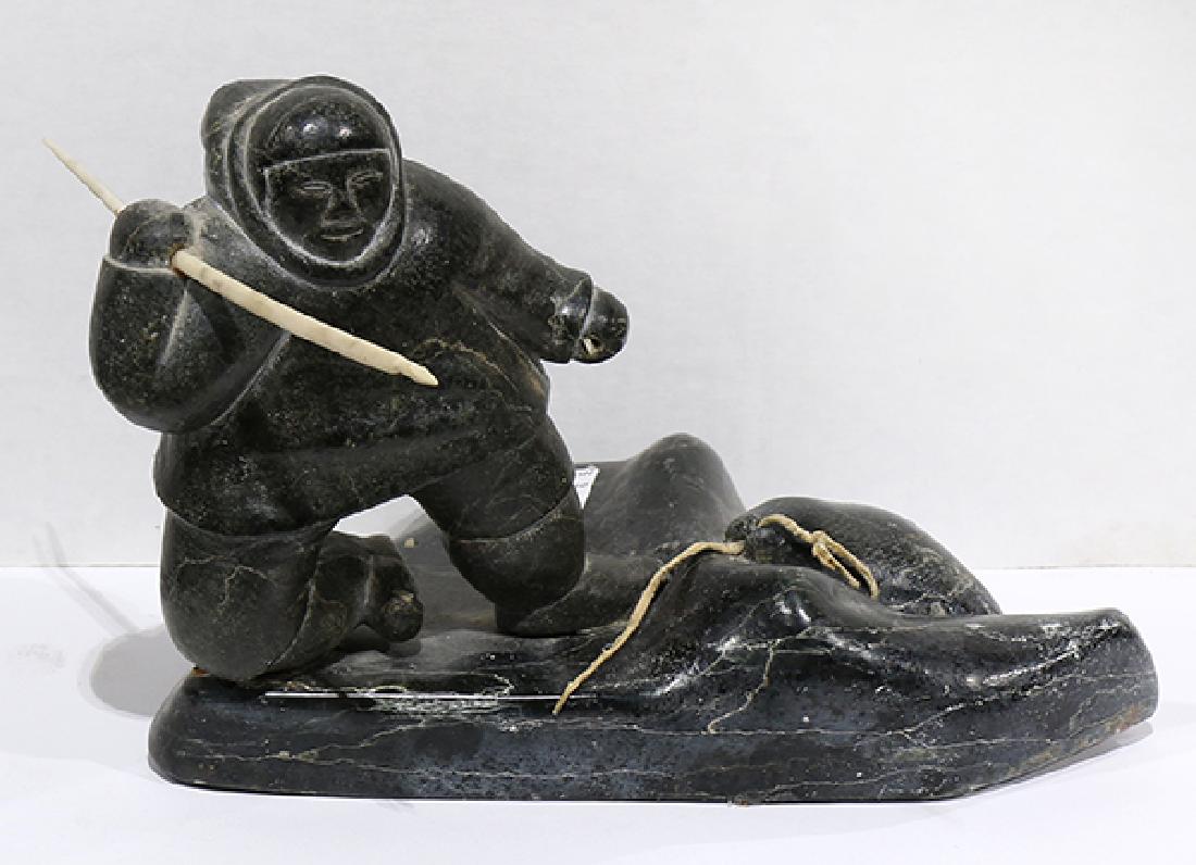 Inuit/Eskimo carving, in the manner of Kapik Kolola: Inuit/Eskimo carving, in the manner of Kapik Kolola (1926-1985), dark green serpentine/hide, depicting an Inuit/Eskimo hunter with a spear dragging a seal out of the water, apparently unsigned, 7"h x 