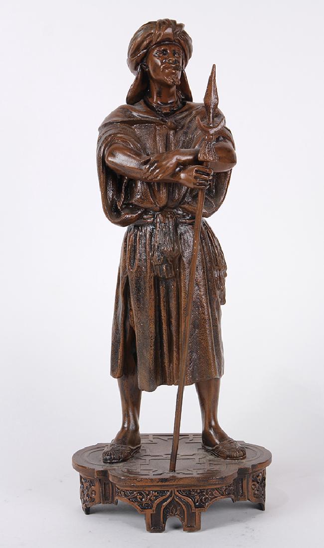 Patinated metal sculpture: Patinated metal sculpture, modeled as a Moorish man standing astride, arms crossed, holding a spear in his right arm, apparently unsigned, 16"h x 6.5"w x 5"d