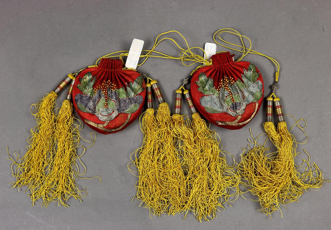 Chinese Red Silk Pouches/Sachets: (lot of 2) Chinese couched silk pouches/sachets, each executed from red satin silk in the form of a peach, metallic couched with peonies, and accented with yellow tassels, 3.25"h