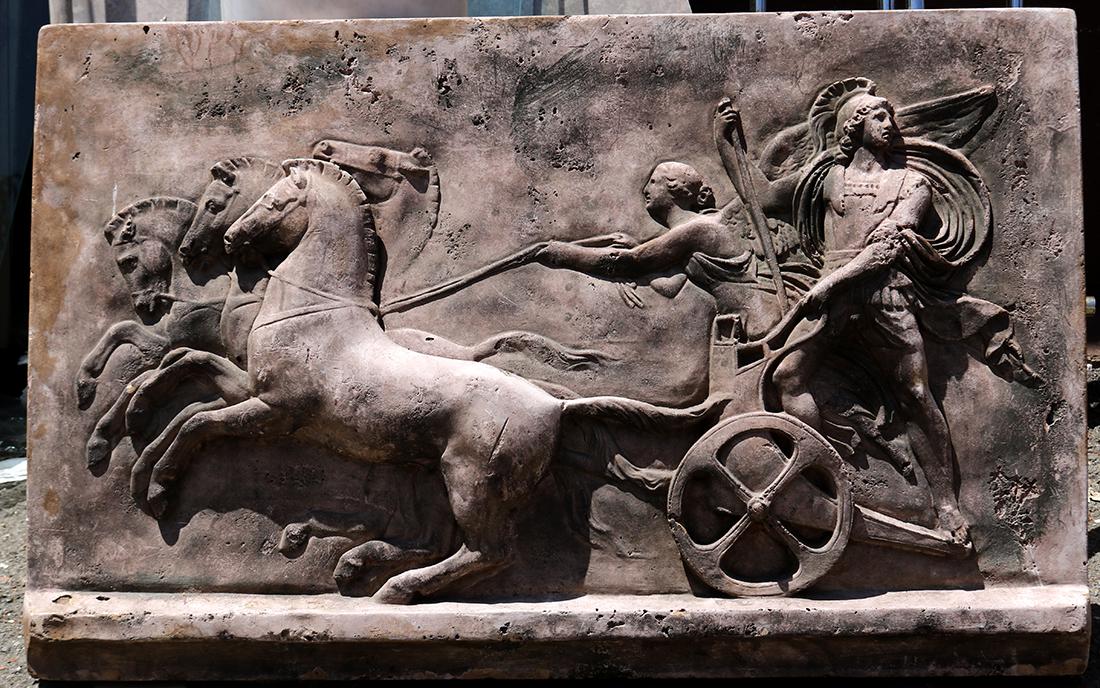 Grand Tour style stone plaque: Grand Tour style stone plaque, depicting a Greco-Roman mythological scene of a winged figure and a classically attired warrior with a chariot and horses, 25"h x 37.5"w x 2"d