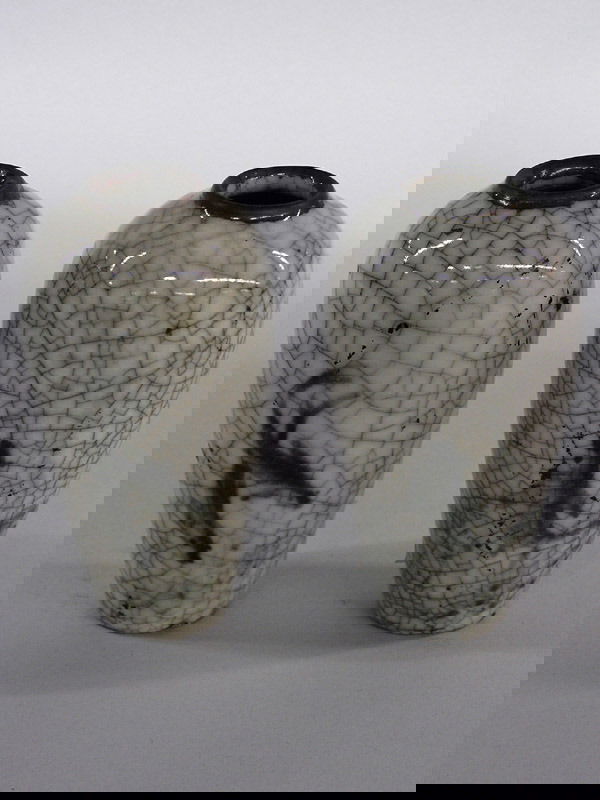 Pair of Chinese ovoid vases: Pair of small Chinese ceramic ovoid vases with underglaze fish design, each of milky white color with overall crackle glaze pattern heightened with black stain, brown rims and foot. Height 4 1/2"