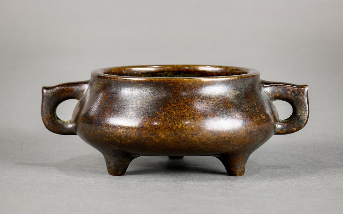 Chinese Tripod Bonze Censer: Chinese patinated bronze tripod censer, with a compressed circular body and flanked by lug handles, the underside with peach shaped 'Xuande' mark, 5.75"w