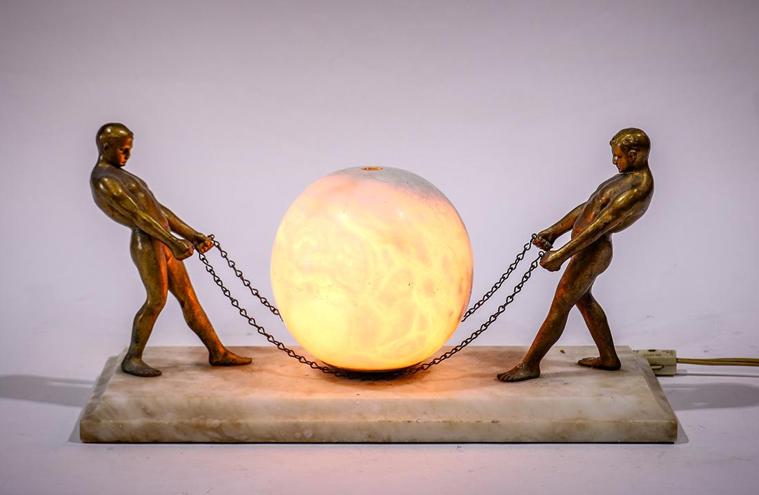 Art Deco style alabaster and enameled metal lamp,: Art Deco style alabaster and enameled metal lamp, depicting two nude men preparing to lift the spherical fixture, 14"l x 6"w
