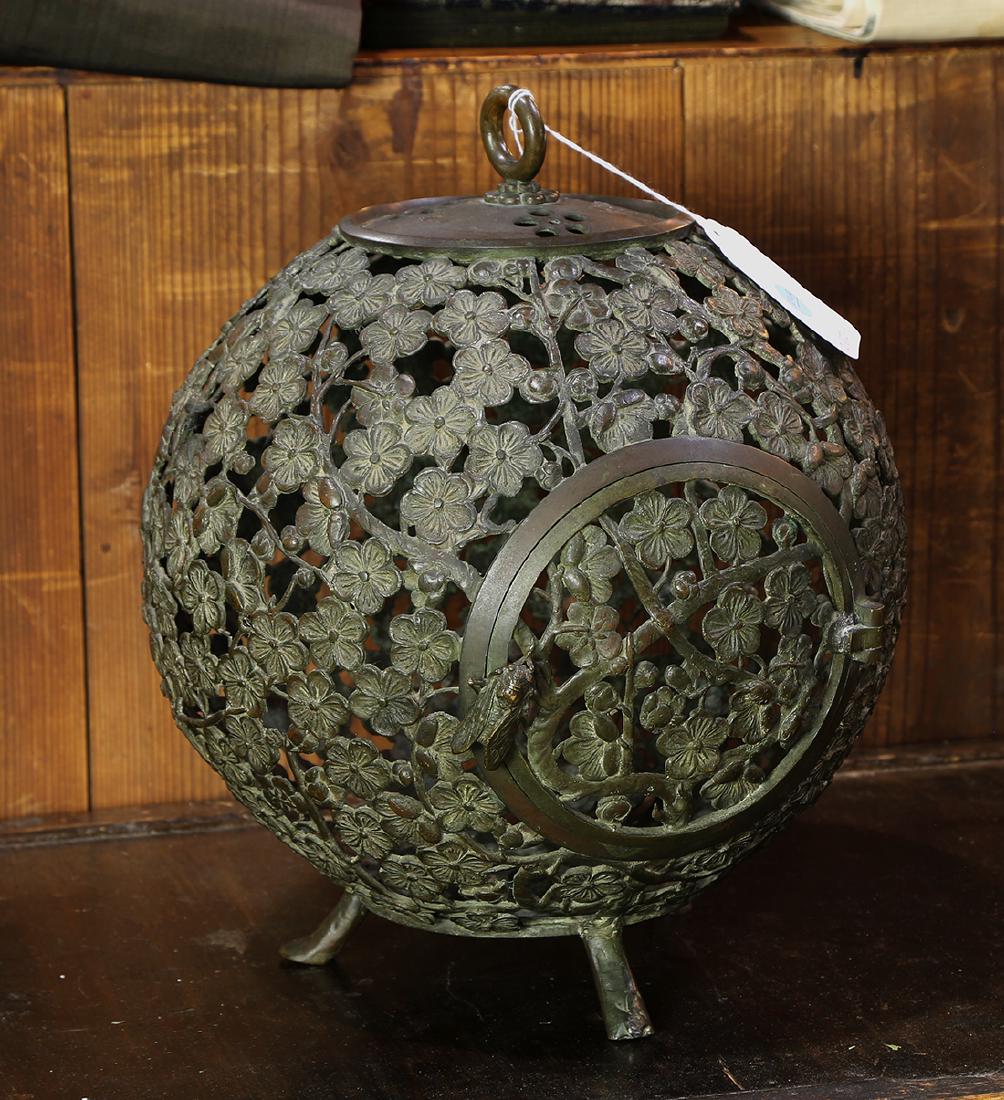 Japanese Bronze Lantern, Hattori: Japanese bronze lantern, global body featuring openwork plum blossoms, roof with a ring handle and plum blossom crests, the circular hinged door opening with a cicada shaped knob, base marked with Hat