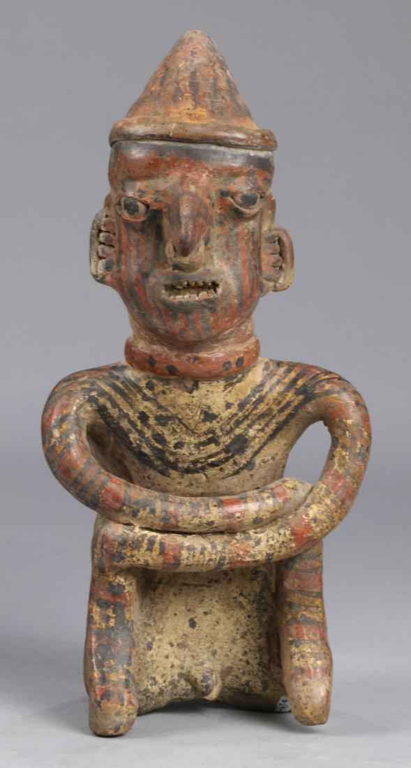 Pre-Columbian polychrome Nayarit figure of a seated: Pre-Columbian polychrome Nayarit figure of a seated shaman, Ixtlan, Del Rio village, Mexico, 200 BC - AD 250, the clay figure seated with arms crossed, with a pointed Shaman's hat, earrings, nose ring