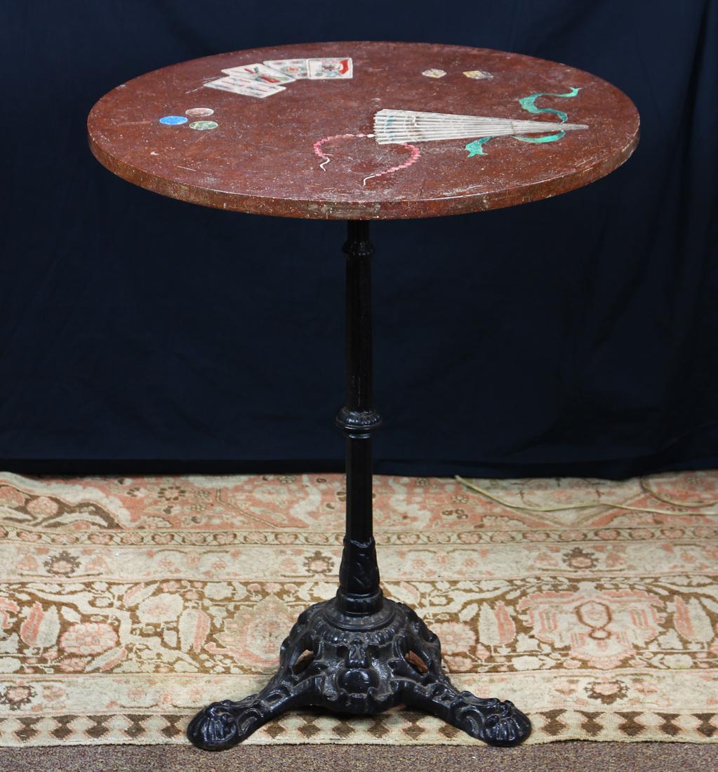 Antique Italian granite card table: Antique Italian granite card table, the circular top inlaid with marble, decorated with cards and dice, above the wrought iron bistro base, having a columnar standard above tripod legs, 28"h Provenanc