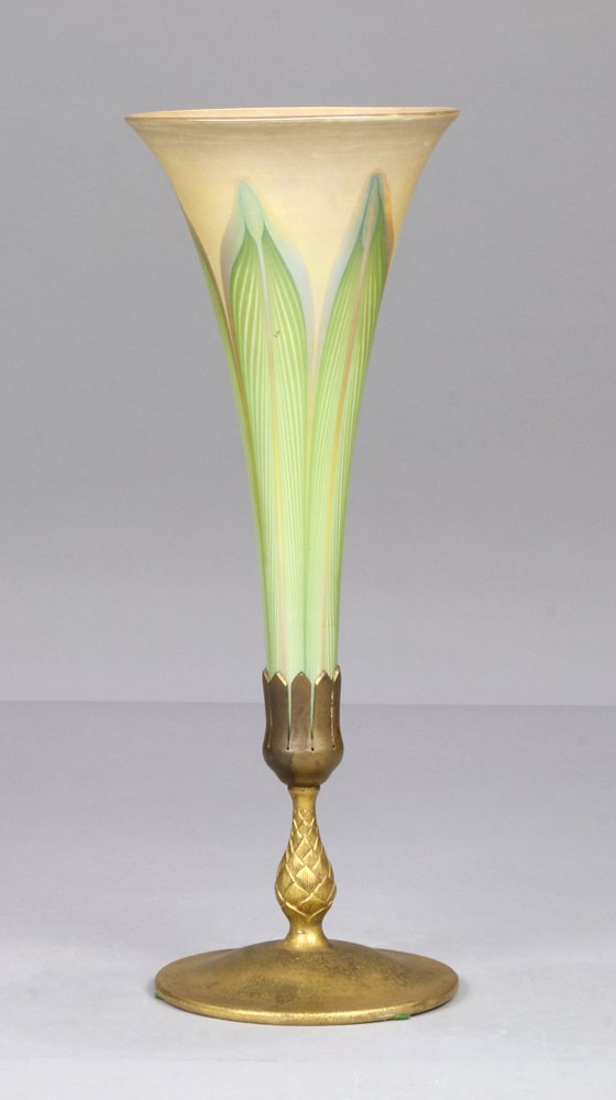 Tiffany Studios dore bronze and favrile glass vase: Tiffany Studios dore bronze and favrile glass vase, having a pulled iridescent trumpet insert rising on the dore base having a pineapple standard, and rising on a circular base marked Tiffany Studios 