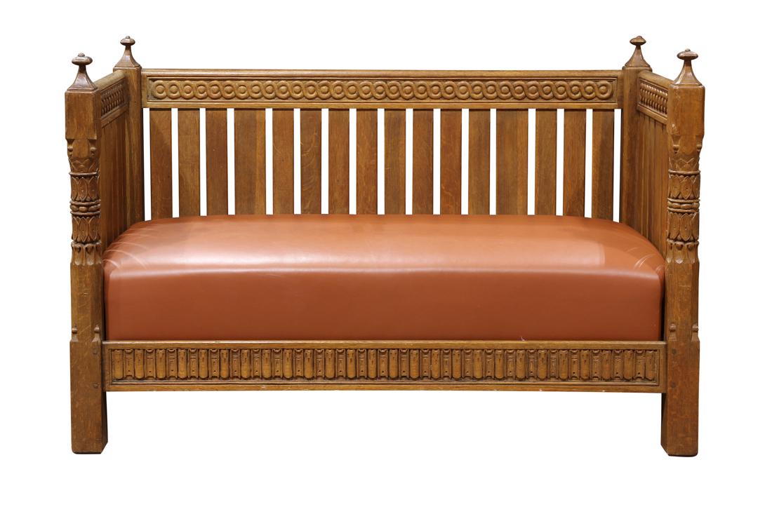 Arts and Crafts even arm settle executed in the Gothic: Arts and Crafts even arm settle executed in the Gothic taste, having carved finials surmounting the relief carved posts continuing to the carved apron, settle with vertical slats, 39.5"h x 60"w x 30"d