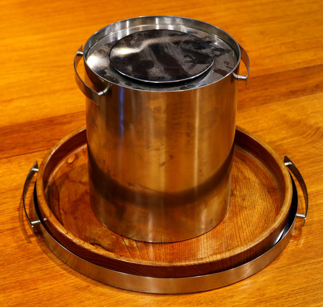 (lot of 2) Arne Jacobsen for Stelton table articles: (lot of 2) Arne Jacobsen for Stelton table articles, including an ice bucket, and a serving tray having a removable wood liner, ice bucket 8"h x 7"w, serving tray 14.5"w