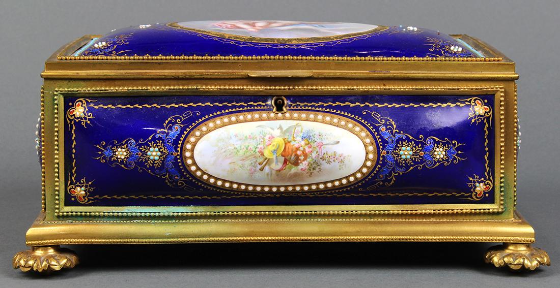 Continental ormolu mounted porcelain and guilloche: Continental ormolu mounted porcelain and guilloche decorated cigar box, with hand-painted figural reserves depicting putti, flowers, etc. and rising on a footed base, 3.5"h x 9"w x 6"d