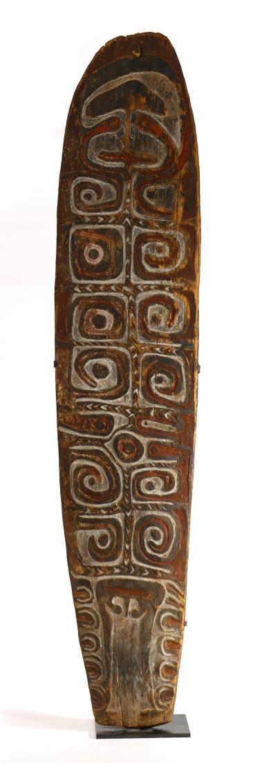 Oceanic carved wood shield: Oceanic carved wood shield, the front having hand carved geometric and figural polychrome decorated reserves, rising on a later metal stand, 40.5"h x 8.5"w