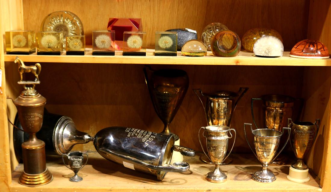One shelf of trophies: (lot of 9) One shelf of trophies, mostly relating to horse racing, including 1920s examples, largest: 20"h
