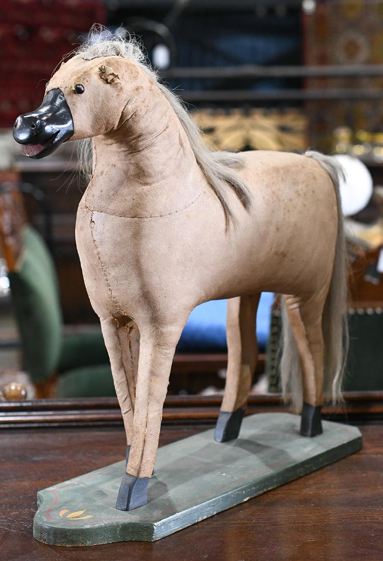 Folk Art horse sculpture: Folk Art horse sculpture, having a hide body with ebonized wood nose and feet, and natural hair mane and tail, rising on a polychrome decorated base, 19"h x 20"l