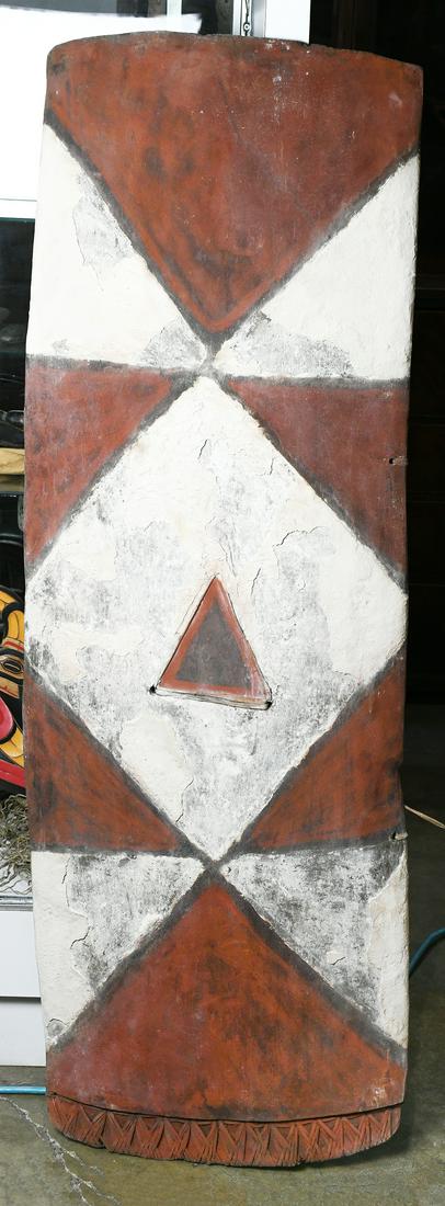 Papua New Guinea carved wood shield, 20th Century,: Papua New Guinea carved wood shield, 20th Century, Maring people, with large triangular panels of alternating red and white pigment, 4'10''h x 1'8''w