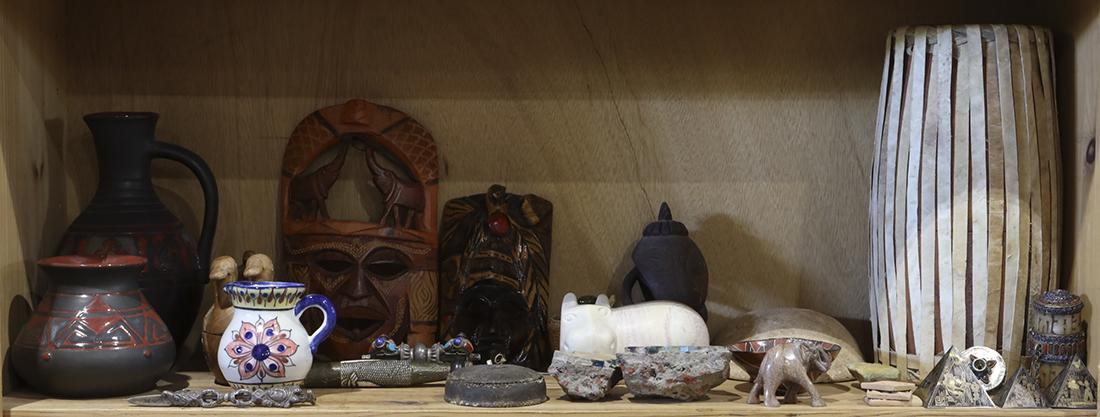 Two shelves of decorative art including Native American: Two shelves of decorative art including Native American style pottery and masks, together with polychrome decorative baskets, etc.