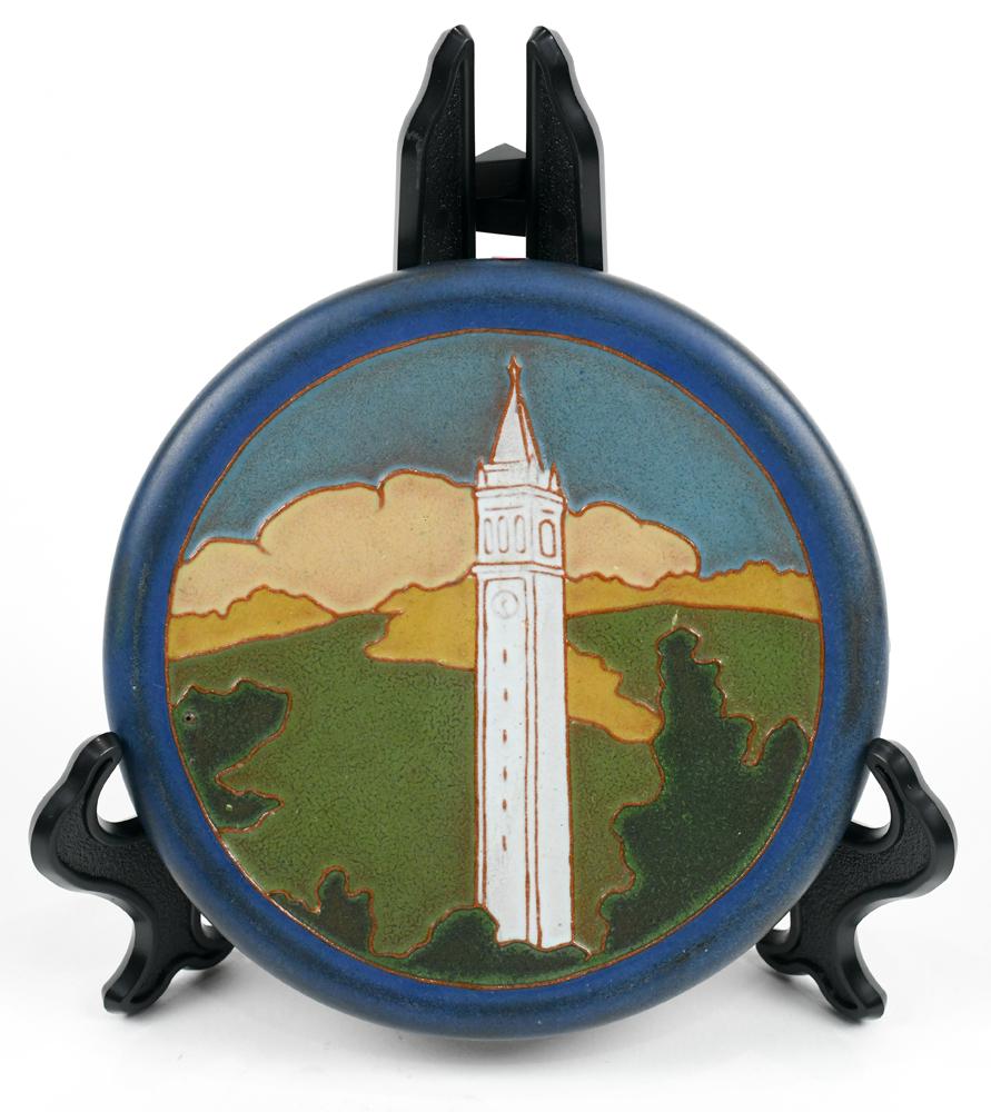(lot of 2) California Faience Art Pottery tile and a: (lot of 2) California Faience Art Pottery tile and a bowl, the circular tubelined tile depicting the University of California Berkeley Campanile against a hilly landscape; together with a blue vase wi