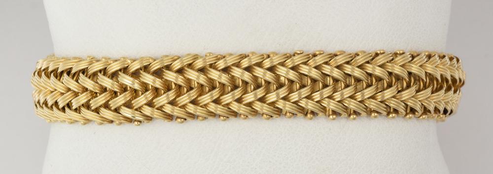 18k yellow gold bracelet: 18k yellow gold bracelet The 18k yellow gold woven link, measuring approximately 11.0 mm in width, completed by a tongue and groove clasp with a figure eight safety and chain, weighing 26.5 grams