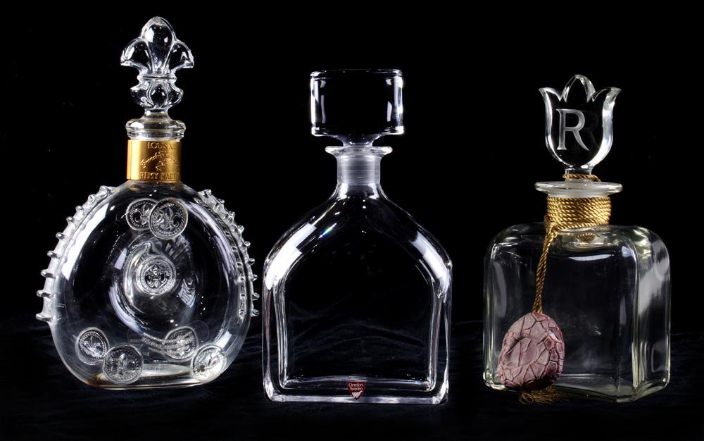 (lot of 3) Decanter group: (lot of 3) Decanter group, consisting of a Baccarat Louis XIII Remy Martin liquor bottle, an Orrefers example, and a Raphael Paris example, the stopper with an etched "R," largest: 11"h; Provenance: T