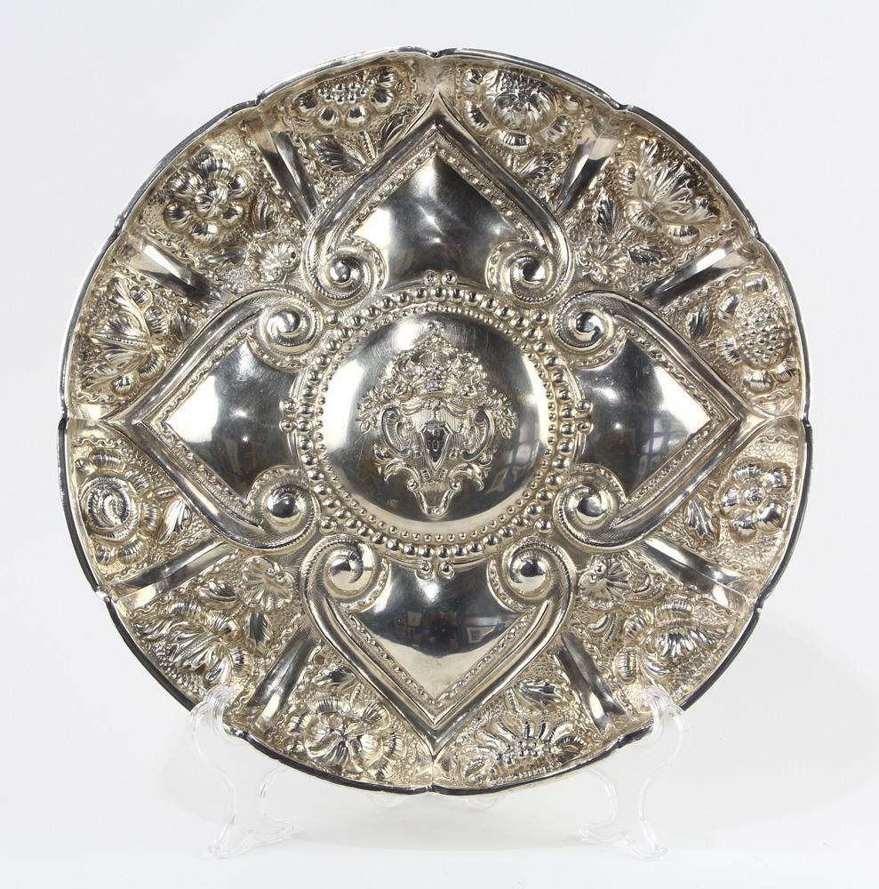 Continental Baroque style repousse silver charger: Continental Baroque style repousse silver charger, the dish form tray centering a coat of arms, enclosed by a collar of heart shaped medallions, an outer band of flowering stems in raised relief, unma