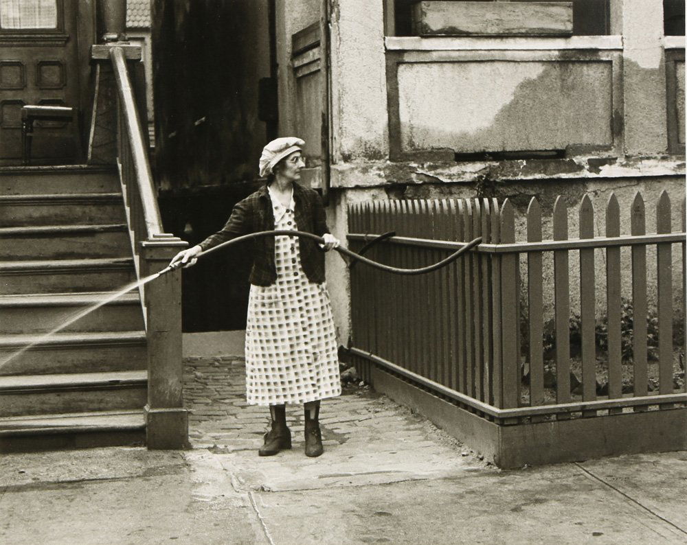 Photograph, Helen Levitt: Helen Levitt (American, 1913-2009), "Woman with Hose," circa 1942, gelatin silver print, pencil signed and dated verso, image: 7.25"h x 8.75"w, overall (with matting): 14.25"h x 18"w
