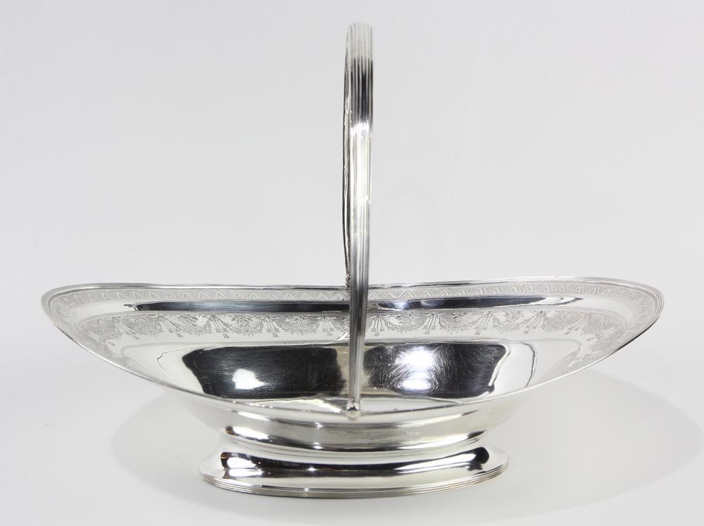 Geore III sterling swing handled basket, Hester: Geore III sterling swing handled basket, Hester Bateman, London, circa 1787, the oblong bowl with a deep well, centering an engraved coat of arms with three phoenix heads, an inner floral swag border