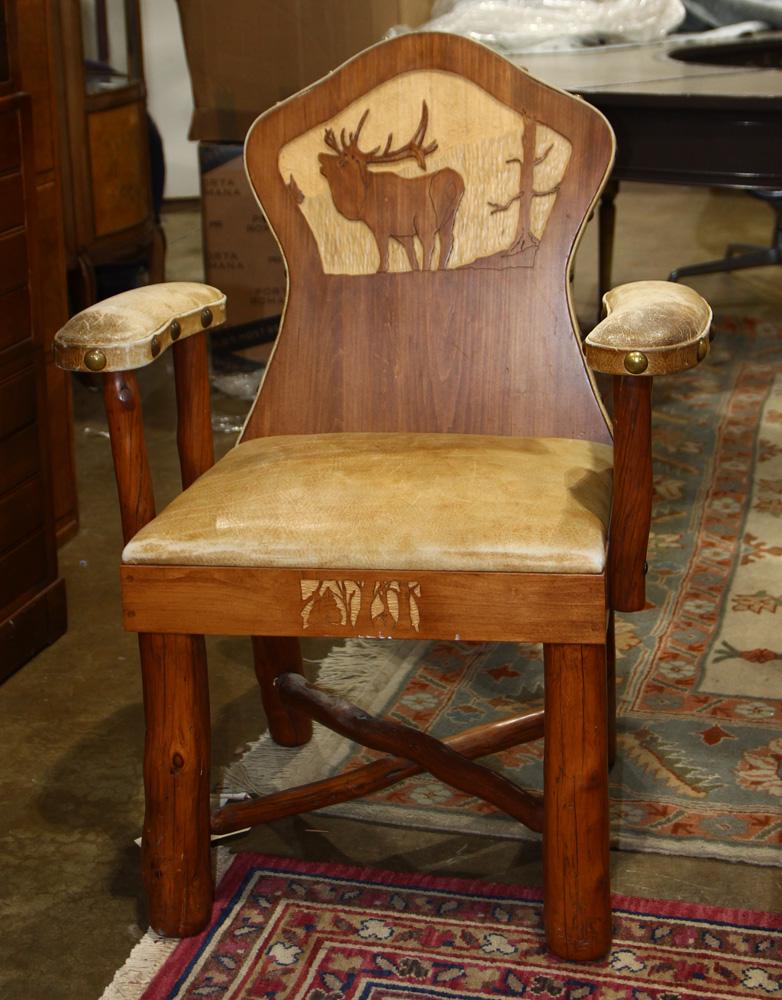 A Lester Santos armchair: A Lester Santos armchair having a shield form back centered with a carved elk reserve and rising on naturalistic legs 37.5"h x 28"w
