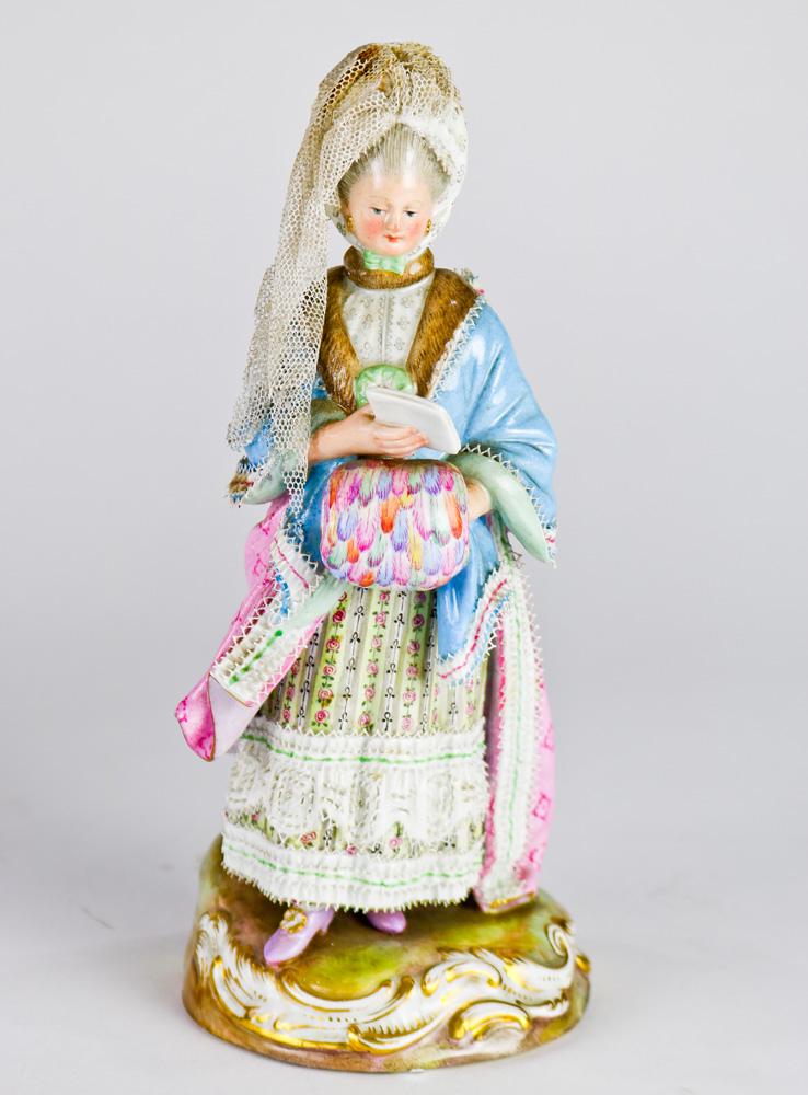 A Meissen figural group: A Meissen figural group, The Reader, depicting a lady with crinoline head cover reading a book, with a highly decorated full length dress continuing to the Rococo style base, marked with cross swords,