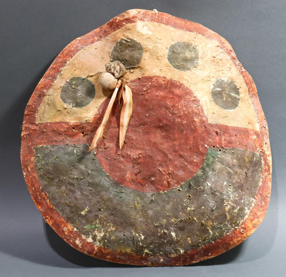 Great Plains American Indian rawhide buffalo shield: A Great Plains American Indian painted rawhide buffalo shield, circa 1880, possibly Kiowa or Comanche, decorated with red, blue and yellow mineral pigments and applied in circular motifs, the front af