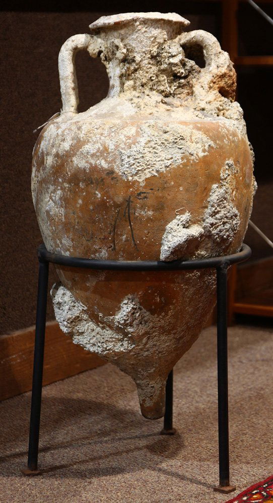 A Roman encrusted redware amphora: Roman encrusted redware amphora, an example of the storage and trade ceramic vessels that occasionally fell to the base of the Mediterranean floor and encrusted with barnacles, and rising on a custom