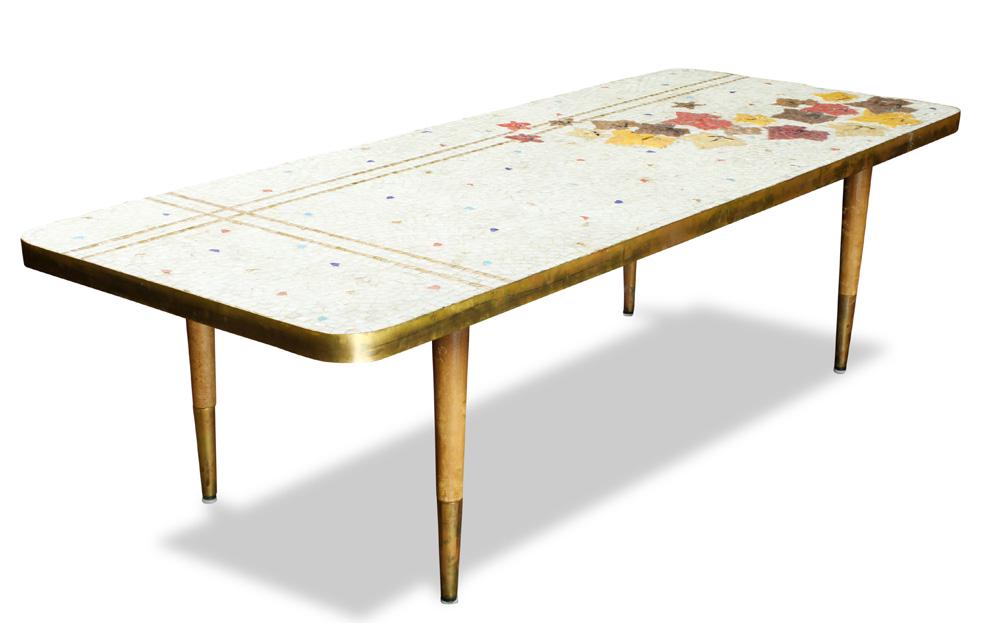 A Genaro Alvarez Mexican occasional table: A Genaro Alvarez Mexican occasional table, having a rectangular mosaic top decorated with polychrome leaves, on a cream ground, and rising on tapered legs terminating on brass caps, 13.5"h x 48"w x 19