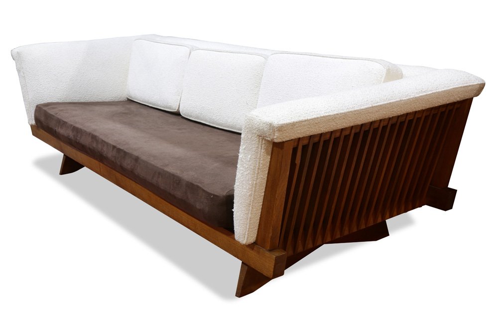 A George Nakashima for Widdicomb even-arm sofa: A George Nakashima for Widdicomb even-arm sofa, executed in walnut, having slat ends, continuing to the original cream boucle upholstery, and rising on shaped slab feet, 26.5"h x 86"w x 34"d