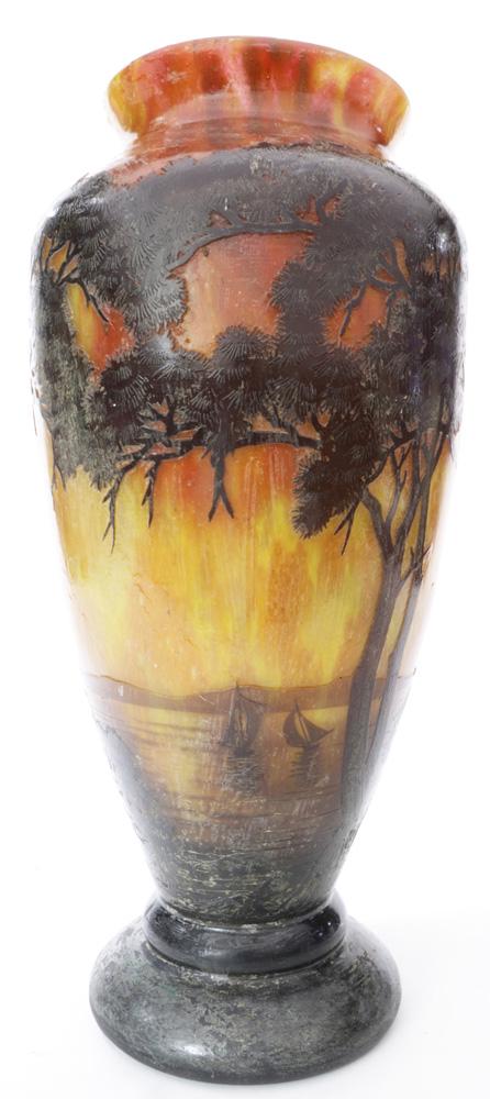 A French three color cameo glass vase: A French three color cameo glass vase, of urn form, depicting a naturalistic scene with trees in the foreground, the sea in the background, signed Daum Nancy to body, underside with a ground pontil, o