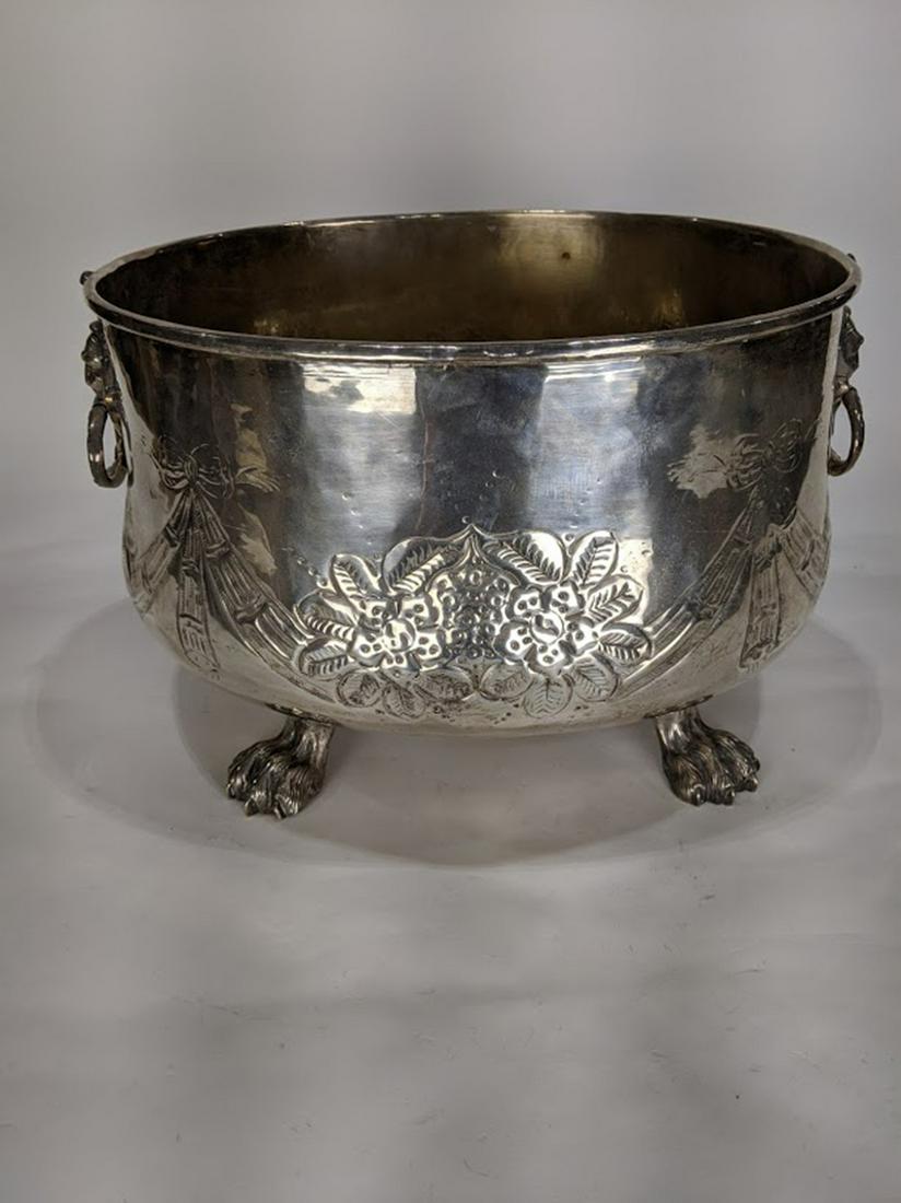 A large Classical style silverplate wine cooler: A large Classical style silverplate wine cooler, likely 19th century, of ovoid form having figural ring form handles, and rising on paw feet, 9"h x 15"w