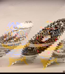 Two Faberge egg replicas with figurine: "Two hand painted porcelain egg shaped boxes with gilt metal mounts 5.5''"