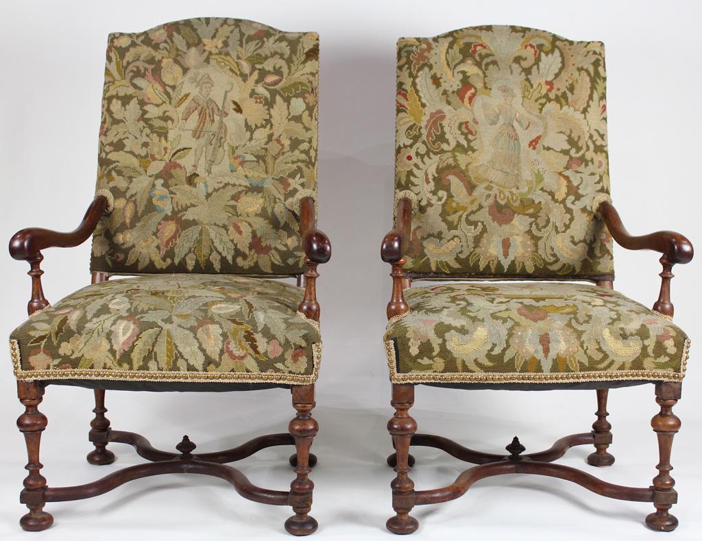 A pair of Continental hall throne chairs: Pair of Continental hall throne chairs, each having a shaped crest above needlepoint fabric, continuing to the scrolled arms, and rising on turned legs, 42.5"h
