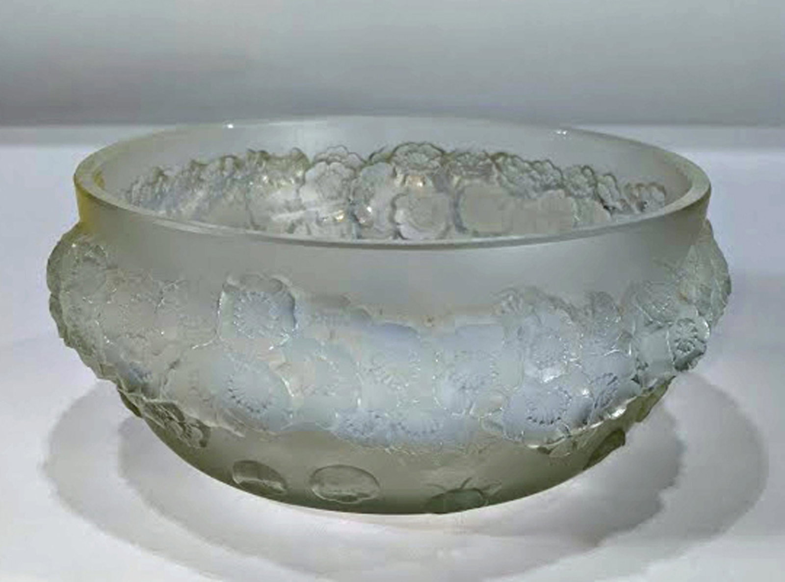 A Lalique Primeveres opalescent glass bowl: Lalique Primeveres opalescent glass bowl, having a tapered form decorated with rosettes, underside with etched R. Lalique mark, 3.5"h x 8.5"dia.