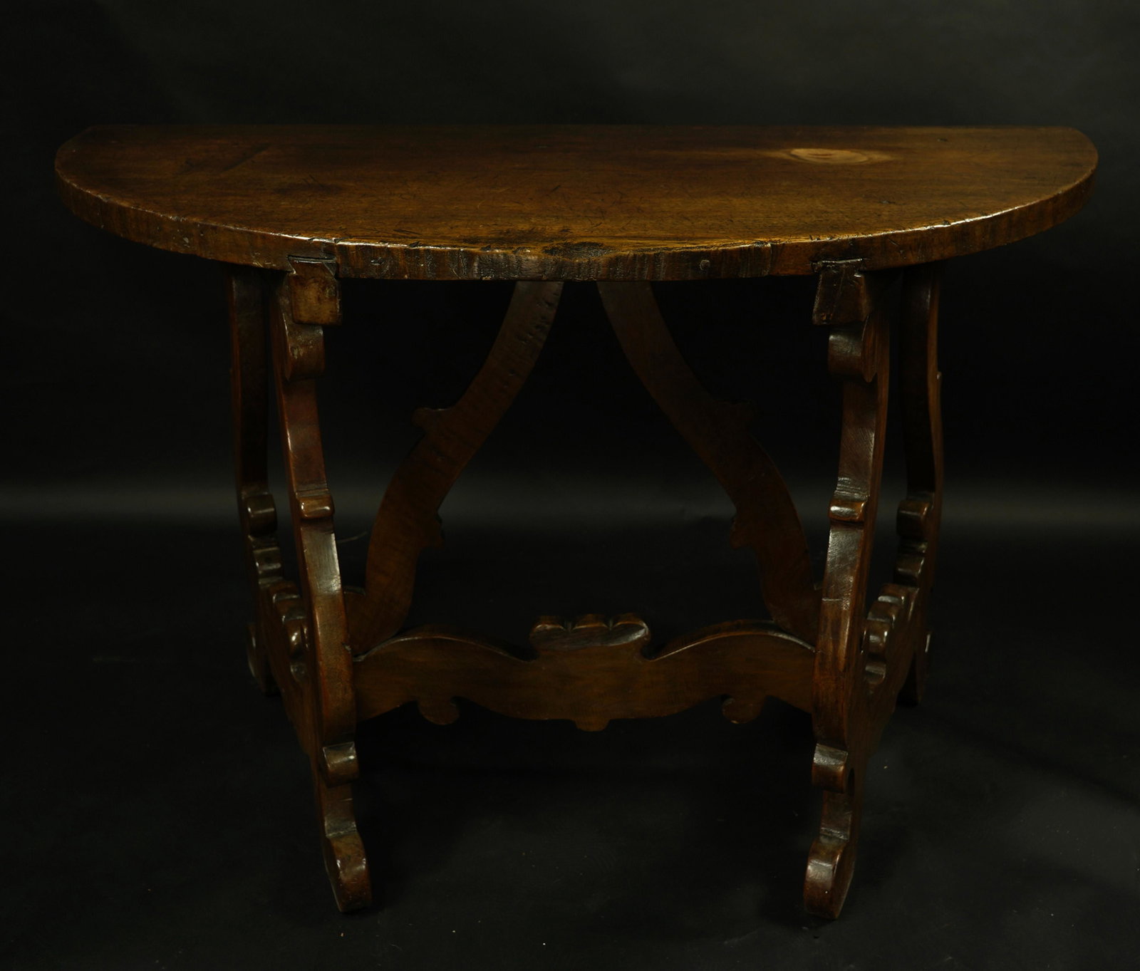 A Baroque style walnut table: Baroque style walnut table, having a demi-lune top, above scolled legs, 30"h x 48"w x 24"d Provenance: Estate of Frank J. Caufield (San Francisco, CA) Note: Mr. Caulfield was one of the founding partn