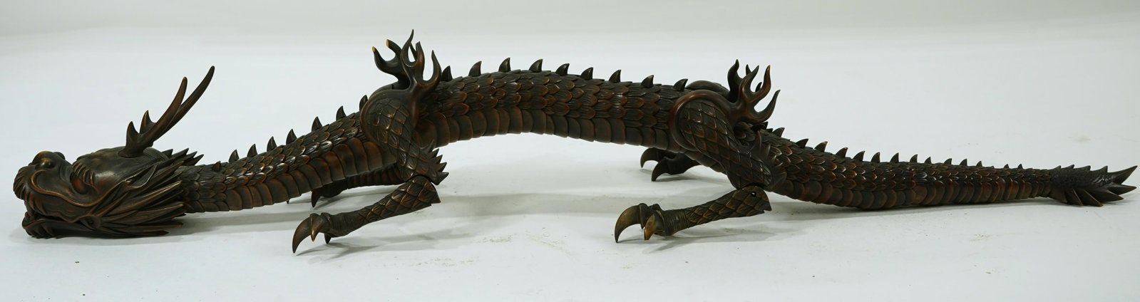 A Japanese carved Fruitwood articulated dragon Meiji: A Japanese carved Fruitwood articulated dragon Meiji Period (Late 19th century), the wood dragon constructed of numerous parts joined inside of the body, the head carved with horns and fitted with a h